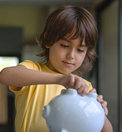 Little boy opening his piggy bank savings